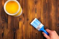 Hand holding a brush over can of paint on a wooden table - Image Royalty Free Stock Photo