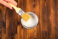 Hand holding a brush over can of paint on a wooden table - Image Royalty Free Stock Photo