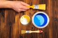 Hand holding a brush over can of paint on a wooden table - Image Royalty Free Stock Photo