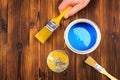 Hand holding a brush over can of paint on a wooden table - Image Royalty Free Stock Photo