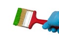 Hand holding Brush with a wooden handle, which is dipped in green paint,