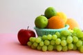 Fresh fruit in the basket apple, lime, avocado, lemon, orange, grapes on a light pink background Royalty Free Stock Photo