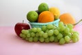 Fresh fruit in the basket apple, lime, avocado, lemon, orange, grapes on a light pink background Royalty Free Stock Photo