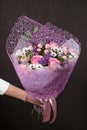 Florist holding a buquet of various flowers on the dark background