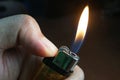 Hand holding burning gas lighters on dark background, Portable device used to create a flame, Close up. Royalty Free Stock Photo