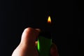 Hand holding burning gas lighters on dark black background. Portable device used to create a flame Royalty Free Stock Photo