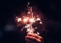 Hand holding burning Sparkler blast on a black background at night,holiday celebration event party,dark vintage tone.