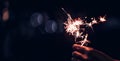 Hand holding burning Sparkler blast on a black bokeh background Royalty Free Stock Photo