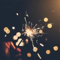 Hand holding burning Sparkler blast on a black bokeh background at night,holiday celebration event party,dark vintage tone Royalty Free Stock Photo