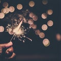 Hand holding burning Sparkler blast on a black bokeh background at night,holiday celebration event party,dark vintage tone Royalty Free Stock Photo