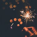 Hand holding burning Sparkler blast on a black bokeh background at night,holiday celebration event party,dark vintage tone Royalty Free Stock Photo