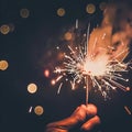 Hand holding burning Sparkler blast on a black bokeh background at night,holiday celebration event party,dark vintage tone Royalty Free Stock Photo