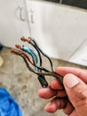 Hand holding burnt and melt down wires from heavy usage electrical device.