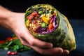 hand holding burrito with vibrant vegetable fillings