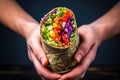 hand holding burrito with vibrant vegetable fillings