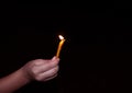 Hand holding a candle lit in the dark night with defocused blurred background Royalty Free Stock Photo