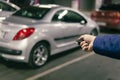 businessman closes his expensive gray car in an underground parking lot. Hand holding a car alarm key with anti-theft Royalty Free Stock Photo