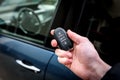 Hand holding a car key with remote control and pushing a button, he is unlocking the door Royalty Free Stock Photo