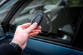 Hand holding a car key with remote control and pushing a button, he is unlocking the door Royalty Free Stock Photo