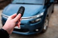 Hand holding a car key with remote control and pushing a button, he is unlocking the door Royalty Free Stock Photo