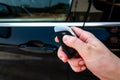 Hand holding a car key with remote control and pushing a button, he is unlocking the door.