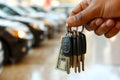 Hand holding car keys on background of salon. Concept of car loan, choice, purchase or rent. Royalty Free Stock Photo