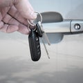 Hand Holding Car Keys in front of Car Door Royalty Free Stock Photo