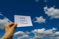 A card which says `VOTE` `Biden` `Trump` with blue sky and clouds