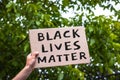 Hand holding cardboard banner with text Black Lives Matter. Anti-racism