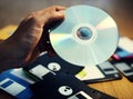 Hand holding CD disk background with floppy on the table