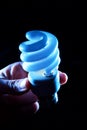 Hand holding cfl blue light-bulb lamp