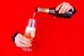 Hand is holding champagne bottle and glass in torn hole Royalty Free Stock Photo