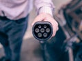 Hand holding and charging electric car with the power cable supply plugged in Royalty Free Stock Photo