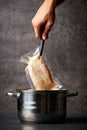 Hand holding chicken breast over cooking pot Royalty Free Stock Photo