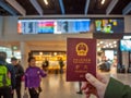 Hand holding a Chinese passport with airport departure hall as background Royalty Free Stock Photo