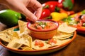 hand holding a chip with queso dip, refried beans, and pico de gallo