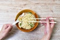 Hand holding chopsticks picking Chinese yellow egg noodles topping slice barbecue pork with red sauce in soup on bowl to eat Royalty Free Stock Photo