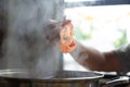 Hand holding chopsticks with pork meat over boiling water hot pot. Thai style, barbecue buffet in Thailand. Shabu or Sukiyaki