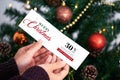 Hand holding christmas gift voucher tags label on christmas tree background