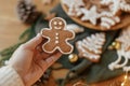 Hand holding christmas gingerbread man cookie with icing against festive table with golden lights and decorations. Merry Christmas Royalty Free Stock Photo