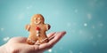 hand holding christmas gingerbreadman on the blue snow background, copy space, poster