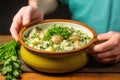 hand holding chunky goulash soup in stoneware pottery