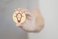 Hand holding circle paper with smiling lightbulb icon in soft focus, smart idea concept Royalty Free Stock Photo