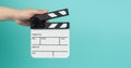 Hand is holding clapper board or clapperboard or movie slate.It is used in film production and movies industry on green mint or