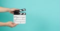 Hand is holding clapper board or clapperboard or movie slate.It is used in film production and movies industry on green mint or
