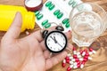 Hand holding clock over table with pills and glass of water Royalty Free Stock Photo