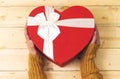 hand holding closed heart shaped box on wood table.