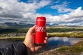 Hand holding a Coca Cola can towards beautiful mountain scenery outdoors in the norwegian wilderness