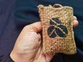 A hand holding a coffee car perfume filled with coffee beans, packaged in an aesthetically pleasing rough burlap material Royalty Free Stock Photo