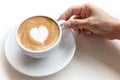 Hand holding coffee cup of latte art heart shape on white background isolated
